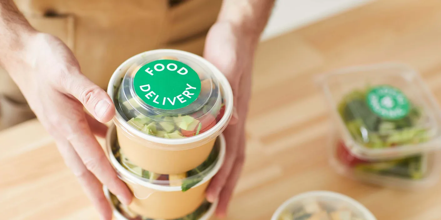 High angle close up of unrecognizable man wearing apron packaging orders while standing by wooden tables, food delivery service worker , copy space